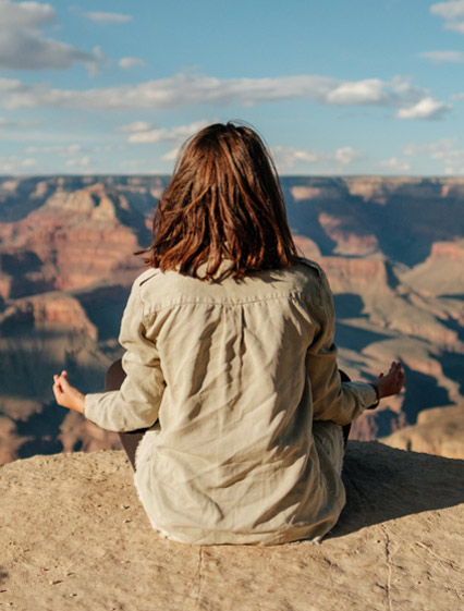 Person meditating on the edge of the Grand Canyon