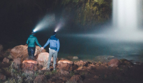 Couple with headlamps looking waterfalls