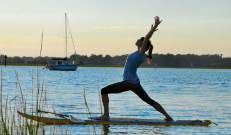 Person practicing yoga on a paddleboard in the water