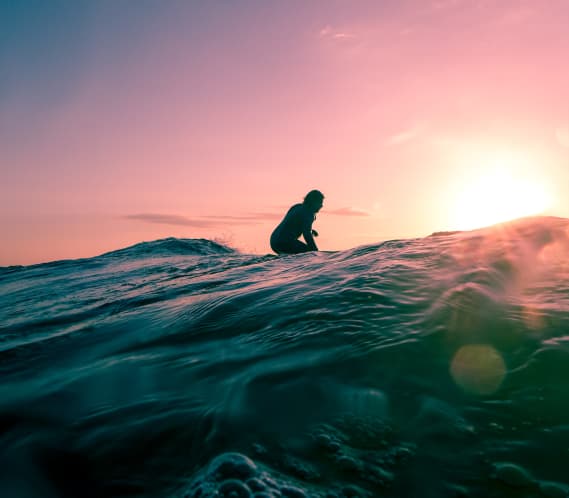 Surfer in the water at sunset